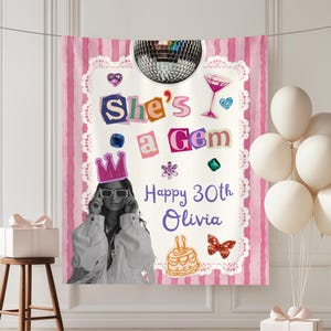 May include: A pink and white striped fabric banner featuring a disco ball, a black and white photograph of a person wearing sunglasses, and the text She's a Gem, Happy 30th Olivia. Decorative elements include a crown, cake, and gems.