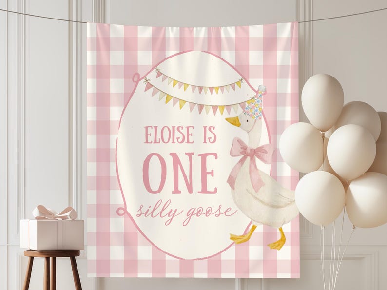 May include: A pink and white gingham backdrop with a banner that reads "Eloise is One silly goose." A cartoon goose wearing a party hat and bow is featured. White balloons and a gift box complete the scene.