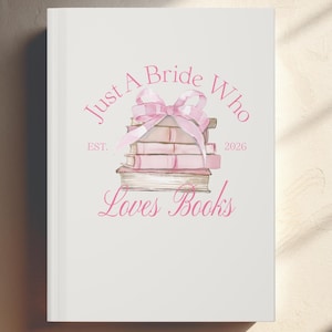 Pode incluir: Capa de livro branca com uma ilustração em aquarela rosa. O design apresenta uma pilha de livros amarrados com um laço rosa e o texto "Just A Bride Who Loves Books" com "EST. 2026".