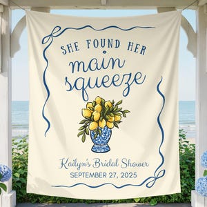 May include: Cream banner with navy blue text and design. The banner says "SHE FOUND HER main squeeze" above a floral illustration of lemons in a blue and white vase. The text "Kailyn's Bridal Shower SEPTEMBER 27, 2025" is at the bottom.