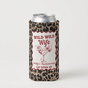 May include: A slim can cooler featuring a brown and black leopard print pattern. A white rectangular label with a scalloped red border displays the text WILD WILD Wife, Emily's Bachelorette, LAS VEGAS, NV, and a graphic of a person in a martini glass.