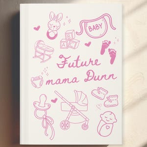 Może przedstawiać: Biały notatnik z różowymi ilustracjami przedmiotów dla niemowląt, w tym kołyski, wózka i bucików. Tekst "Future mama Dunn" jest napisany różowym pismem.