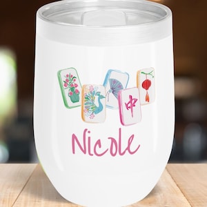 May include: White insulated wine tumbler with a silver rim and lid. The tumbler features a watercolor design of five Mahjong tiles and the name "Nicole" in pink script. The tiles have floral, bird, and Chinese symbol designs.