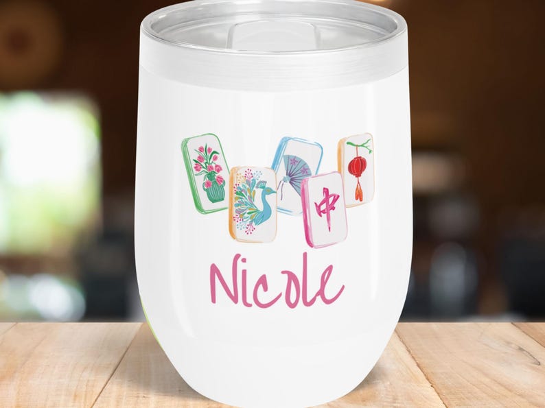 May include: White insulated wine tumbler with a silver rim and lid. The tumbler features a watercolor design of five Mahjong tiles and the name "Nicole" in pink script. The tiles have floral, bird, and Chinese symbol designs.