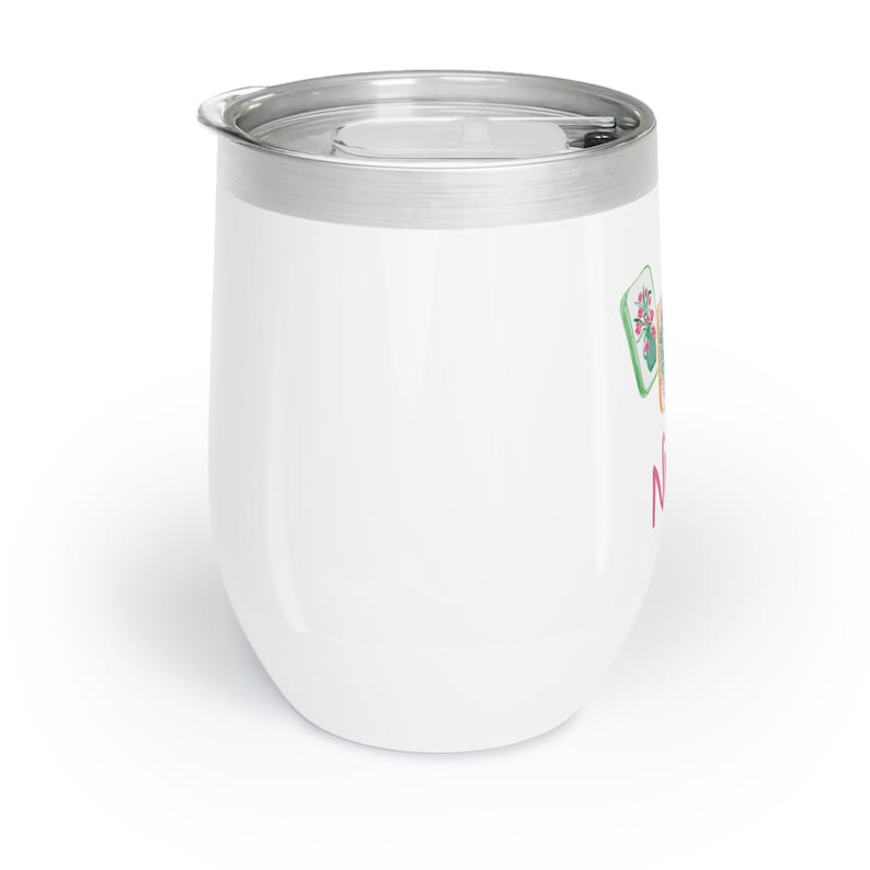 May include: White insulated wine tumbler with a silver rim and lid. The tumbler features a colorful floral design and the word "N" in pink. The tumbler is designed to keep beverages cold for hours.