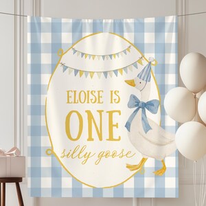 May include: A birthday banner with a blue and white gingham pattern background. The banner features a cartoon goose wearing a party hat and bow tie. Text on the banner reads "Eloise is One silly goose". White balloons and a gift box complete the party scene.