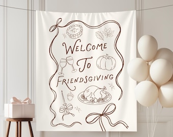 May include: A cream-colored fabric wall hanging featuring a brown line-art border and the text "Welcome To Friendsgiving". The design includes illustrations of a pie, leaves, wine glasses, a pumpkin, a roasted turkey, and a candle with a bow.