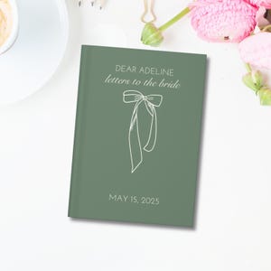May include: A green journal with the text "Dear Adeline letters to the bride" and a white bow illustration. The date "May 15, 2025" is printed below the bow.