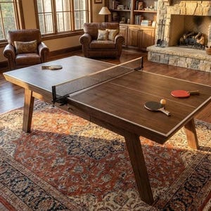 May include: A wooden ping pong table with a net, bats, and a ball. The table is brown with a white border and sits on a patterned rug. The room has leather armchairs, a fireplace, and a piano.
