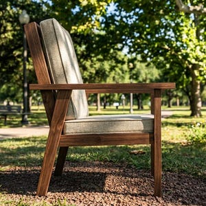 Puede incluir: Silla de exterior de madera con coj&iacute;n y reposabrazos de color gris claro. La silla es de madera marr&oacute;n oscuro y est&aacute; colocada sobre un lecho de peque&ntilde;as rocas y hierba. El fondo presenta un parque con &aacute;rboles y un sendero.