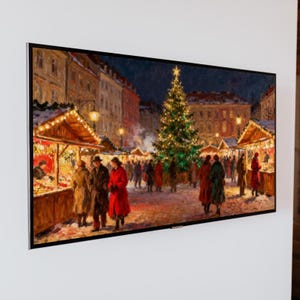 May include: A framed painting depicts a Christmas market scene. The artwork showcases a decorated Christmas tree, market stalls with lights, and figures in winter coats. The color palette includes warm tones of red, gold, and brown, creating a festive atmosphere.