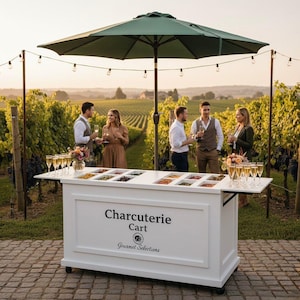 May include: A white charcuterie cart with a green umbrella, set in a vineyard. The cart has a display of food items and the text "Charcuterie Cart" and "Gourmet Selections". Several people are gathered around, holding glasses of champagne.