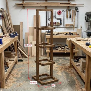 K&ouml;nnte beinhalten: Ein handgefertigter Pflanzenst&auml;nder aus Holz mit dunkler Beize. Der St&auml;nder hat eine rechteckige Basis, vier quadratische Regale und misst 156 cm hoch, 39,4 cm breit und 45,7 cm tief. Der St&auml;nder ist f&uuml;r die Pr&auml;sentation von Pflanzen oder Dekorationsartikeln konzipiert.