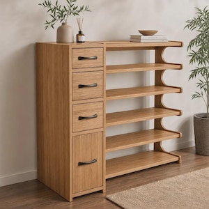 May include: A light brown wooden storage unit featuring three stacked drawers and one larger bottom cabinet door, each equipped with a black curved handle. To the right, five open shelves are supported by curved side panels.
