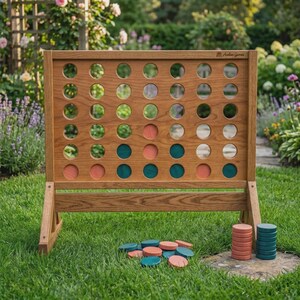 Puede incluir: Un tablero de juego de cuatro en raya de madera con una cuadr&iacute;cula de aberturas circulares, que presenta el texto Avalon Games en la esquina superior derecha. El tablero contiene varias fichas circulares de color cerceta y melocot&oacute;n.