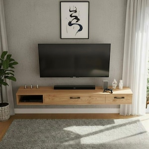 May include: A modern, floating wooden entertainment center with a black TV mounted above. The center features drawers, a shelf, and a soundbar. A framed abstract art piece hangs above the TV. A gray rug is on the floor.