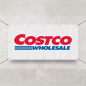 May include: White banner with the red "Costco" logo and the blue "Wholesale" text. The banner is rectangular and has grommets along the top and bottom edges. Black cords are attached to the corners.