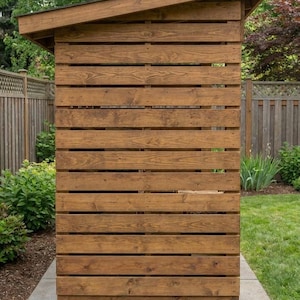 May include: A wooden shed with a sloping roof, built from horizontal planks. The shed is stained a warm brown and rests on a concrete base. The background features a green lawn and trees.