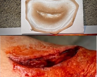 May include: A realistic, prosthetic wound, featuring a deep laceration with exposed tissue and simulated blood. The top image shows a latex wound on a white surface, secured with pins. The bottom image shows a close-up of the wound.
