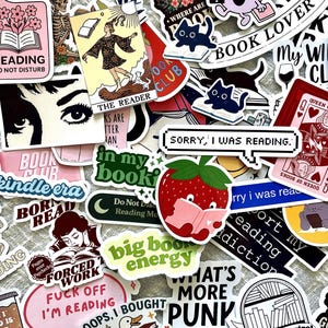 Op de afbeelding: Een verzameling kleurrijke stickers met diverse ontwerpen en tekst. De stickers bevatten illustraties van boeken, katten, tarotkaarten en humoristische zinnen zoals "Sorry, I was reading." en "Big book energy."