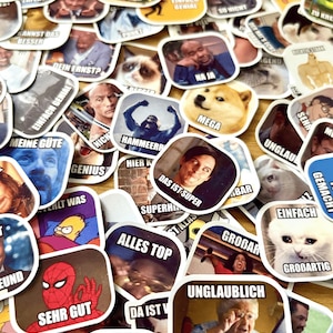 Op de afbeelding: Een verzameling vierkante stickers met memes en internet humor. De stickers tonen afbeeldingen van beroemdheden, stripfiguren en dieren, samen met humoristische tekst in meerdere talen. De stickers zijn verspreid over een lichtgekleurd oppervlak.