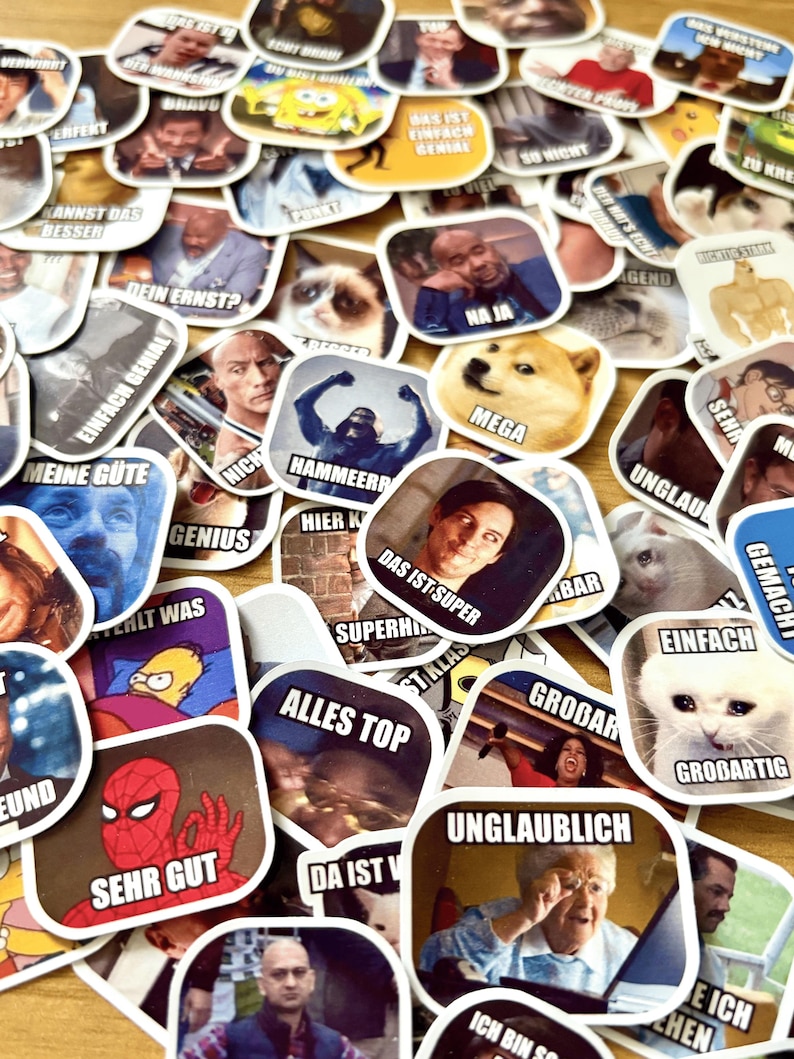 Op de afbeelding: Een verzameling vierkante stickers met memes en internet humor. De stickers tonen afbeeldingen van beroemdheden, stripfiguren en dieren, samen met humoristische tekst in meerdere talen. De stickers zijn verspreid over een lichtgekleurd oppervlak.