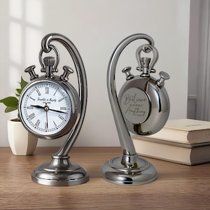 May include: Two silver-toned decorative clocks. One clock has a white face with black Roman numerals and the text "Franklin & Murphy EST. 1869". The other clock has the text "Believe in Yourself, Anything is Possible".