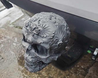 May include: A 3D printed skull with intricate, detailed designs. The skull is gray and has a textured surface.