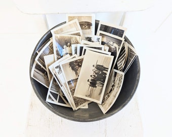 May include: A metal bowl filled with a collection of black and white vintage photographs.