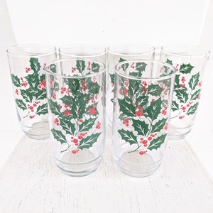 May include: Set of six clear glass drinking glasses with a holly and berry design. The glasses have a green holly leaf pattern with red berries.