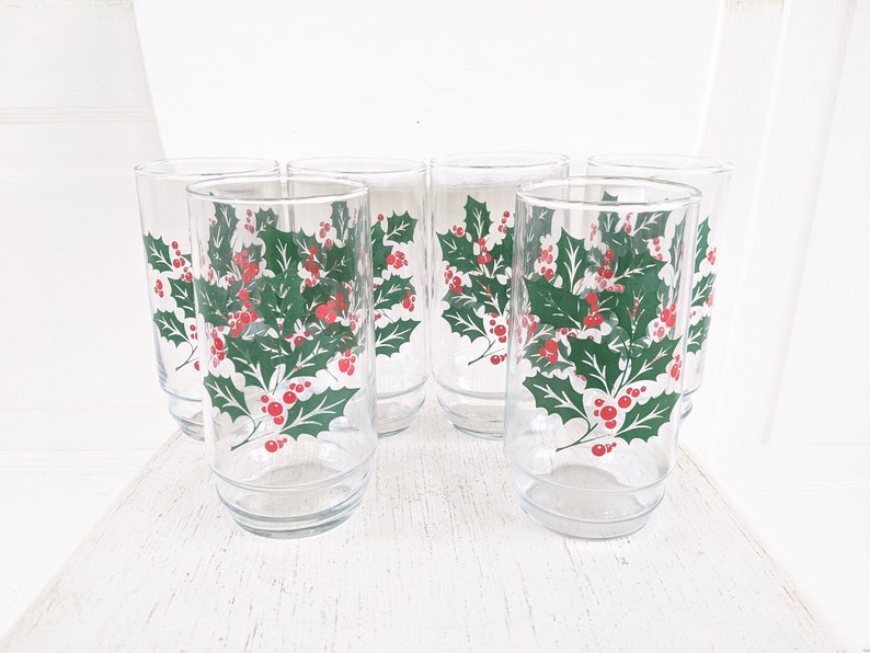 May include: Set of six clear glass drinking glasses with a green holly and red berry design.