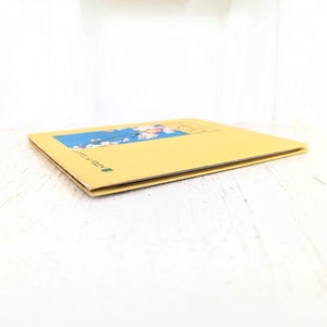 Pode incluir: Um livro amarelo com um design floral azul e branco na capa. O livro &eacute; intitulado "Made in Italy".