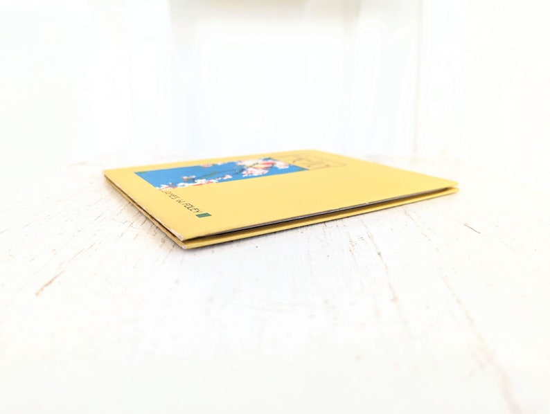 Pode incluir: Um livro amarelo com um design floral azul e branco na capa. O livro &eacute; intitulado "Made in Italy".