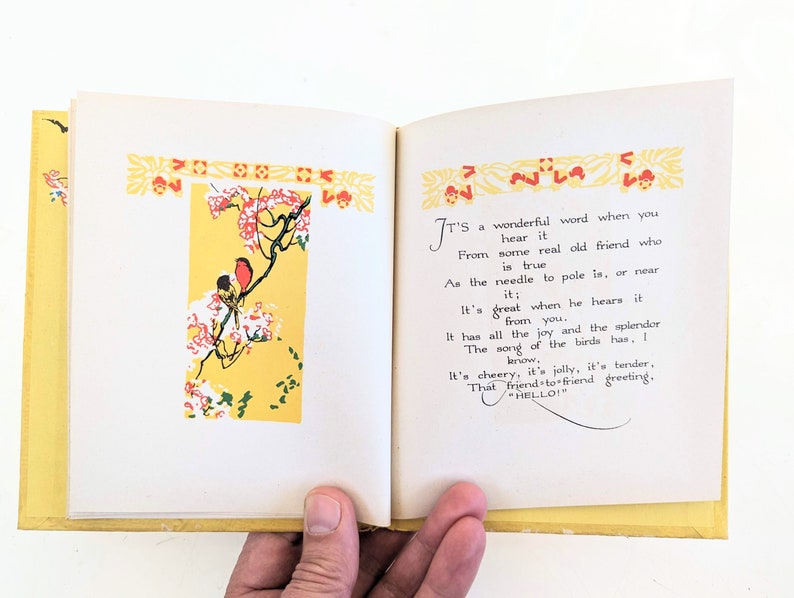 Pode incluir: Um livro aberto com p&aacute;ginas amarelas e uma ilustra&ccedil;&atilde;o colorida de p&aacute;ssaros em um galho. O texto na p&aacute;gina diz "&Eacute; uma palavra maravilhosa quando voc&ecirc; a ouve de um velho amigo de verdade que &eacute; verdadeiro como a agulha para o p&oacute;lo &eacute;, ou perto dele; &Eacute; &oacute;timo quando ele a ouve de voc&ecirc;. Tem toda a alegria e o esplendor A can&ccedil;&atilde;o dos p&aacute;ssaros tem, voc&ecirc; sabe. &Eacute; alegre, &eacute; alegre, &eacute; terno, Essa sauda&ccedil;&atilde;o de amigo para amigo, "OL&Aacute;!" "