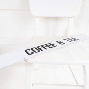 Puede incluir: Silla de madera blanca con un letrero blanco que dice "Coffee & Tea" en la parte superior.