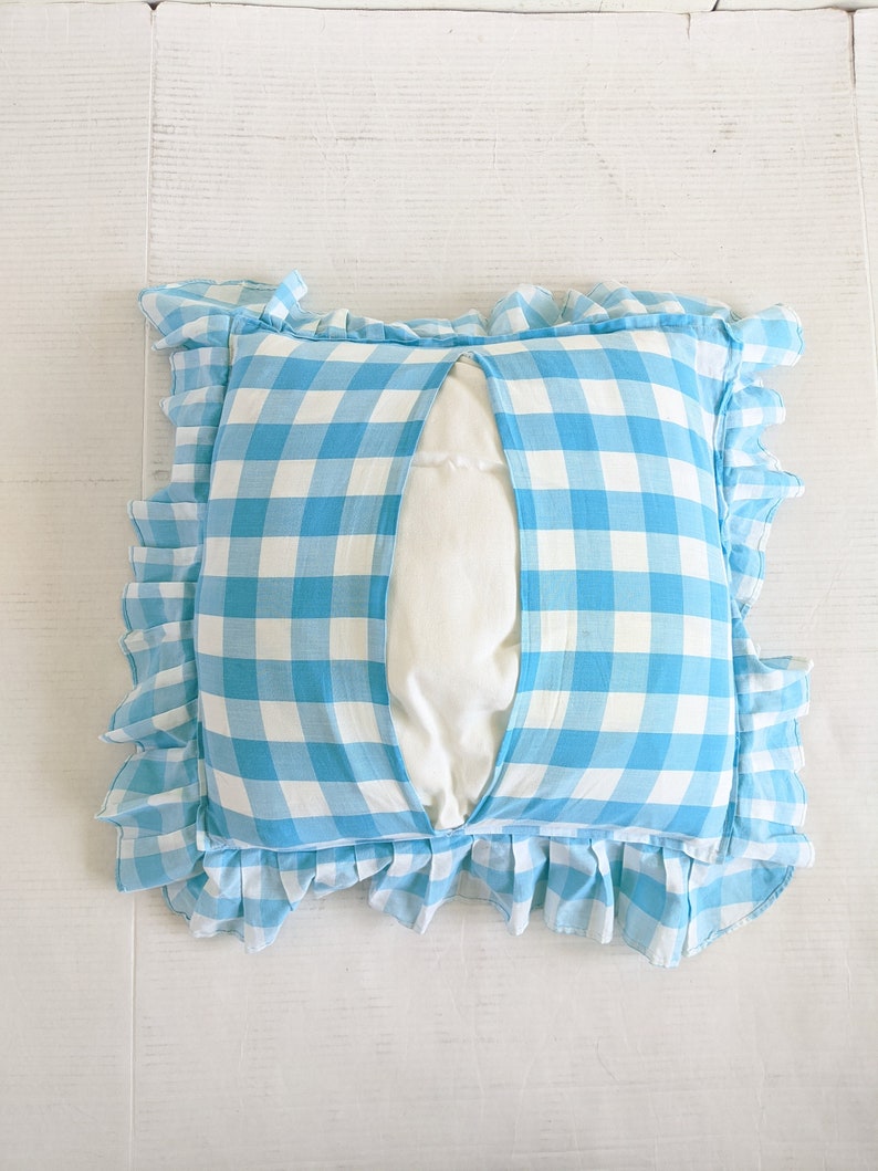 Op de afbeelding: Een blauw en wit geruit kussen met een gerimpelde rand. Het kussen heeft een witte inzet die zichtbaar is door een spleet in de voorkant van het kussen.