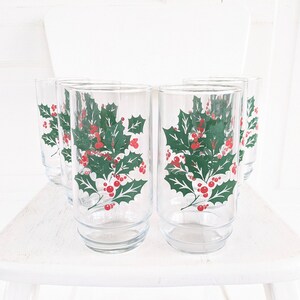 May include: Set of six clear glass tumblers with a holly and berry design. The glasses have a green holly leaf pattern with red berries.