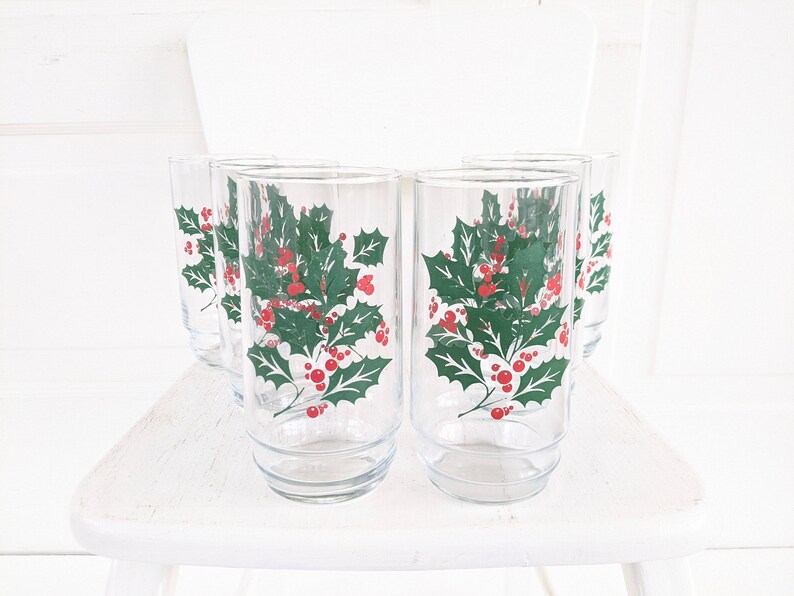 May include: Set of six clear glass tumblers with a holly and berry design. The glasses have a green holly leaf pattern with red berries.