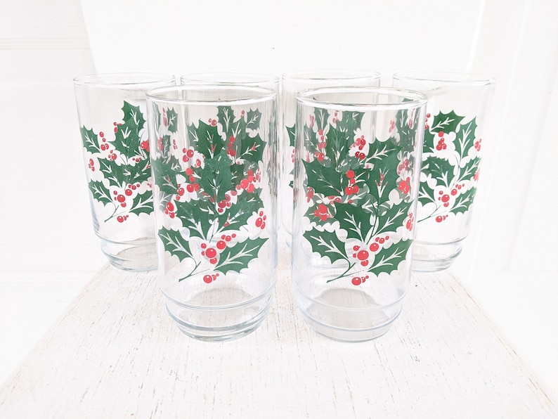 May include: Set of six clear glass drinking glasses with a holly and berry design. The glasses are perfect for holiday entertaining.
