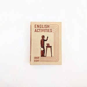 K&ouml;nnte beinhalten: Vintage "English Activities" Lehrbuch der achten Klasse. Das Cover zeigt eine braune Illustration einer Person, die zeigt, neben einem kleinen Tisch mit einem Krug. Titel und Klasse sind in einem rotbraunen Farbton gehalten.