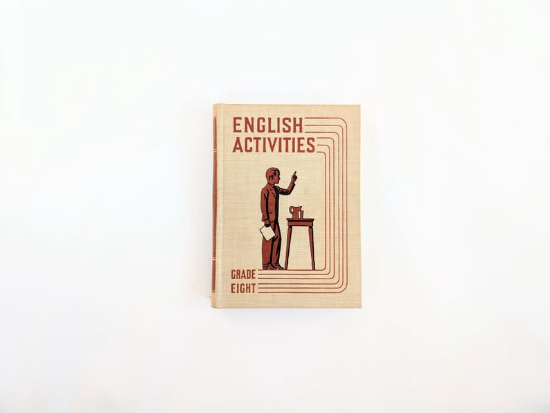 K&ouml;nnte beinhalten: Vintage "English Activities" Lehrbuch der achten Klasse. Das Cover zeigt eine braune Illustration einer Person, die zeigt, neben einem kleinen Tisch mit einem Krug. Titel und Klasse sind in einem rotbraunen Farbton gehalten.