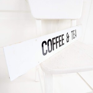 Puede incluir: Silla de madera blanca con un letrero blanco que dice "COFFEE & TEA".