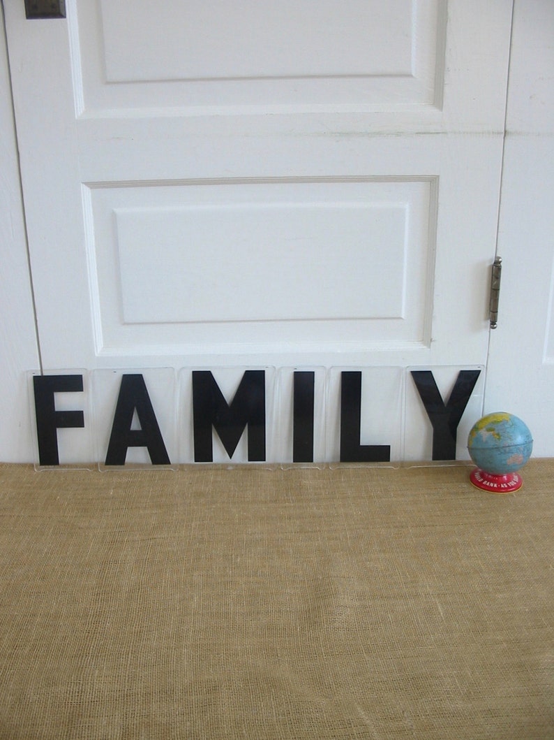 May include: Black block letters spelling out the word "FAMILY" on a burlap surface with a small globe on the right side of the image.