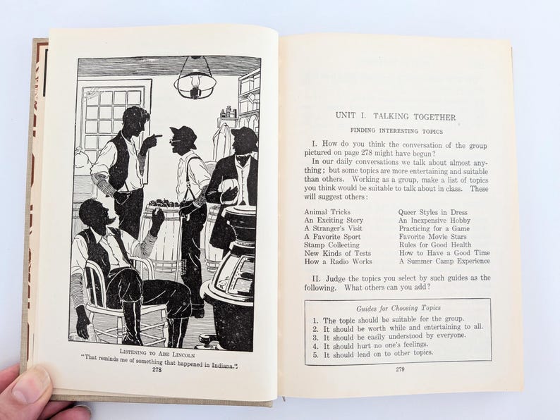 K&ouml;nnte beinhalten: Ein offenes Buch mit Illustrationen und Text. Die linke Seite zeigt eine Schwarz-Wei&szlig;-Illustration von M&auml;nnern in einem Raum. Die rechte Seite hat den Text "Talking Together" und eine Liste von Themen.