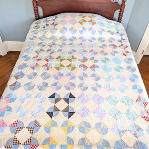 Puede incluir: Colcha hecha a mano con dise&ntilde;o de patchwork colorido, con una variedad de telas pastel y brillantes. La colcha est&aacute; sobre un marco de cama de madera, mostrando una mezcla de patrones geom&eacute;tricos y estampados florales. Dimensiones: aproximadamente 203 cm x 229 cm.