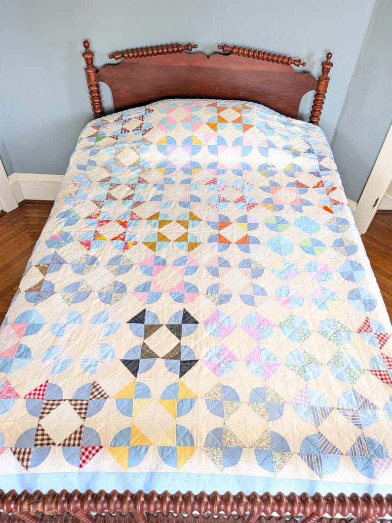 Puede incluir: Colcha hecha a mano con dise&ntilde;o de patchwork colorido, con una variedad de telas pastel y brillantes. La colcha est&aacute; sobre un marco de cama de madera, mostrando una mezcla de patrones geom&eacute;tricos y estampados florales. Dimensiones: aproximadamente 203 cm x 229 cm.