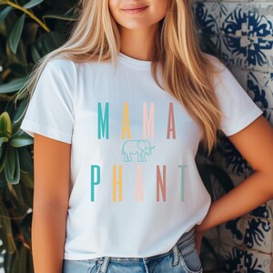May include: A white t-shirt with the text "MAMA PHANT" in colorful letters. The word "MAMA" is in teal, yellow, pink, and orange. The word "PHANT" is in teal, yellow, pink, and light blue. A small outline of an elephant is between the words.
