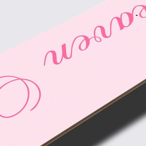 May include: A light pink skateboard deck with the cursive text "So Heaven" in a darker pink. The deck has a wooden edge and is set against a light gray background.