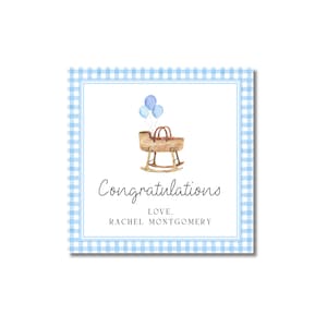 May include: Square card with a blue gingham border and a white interior. The card features a watercolor illustration of a baby cradle with blue balloons. The text reads "Congratulations, Love, Rachel Montgomery."