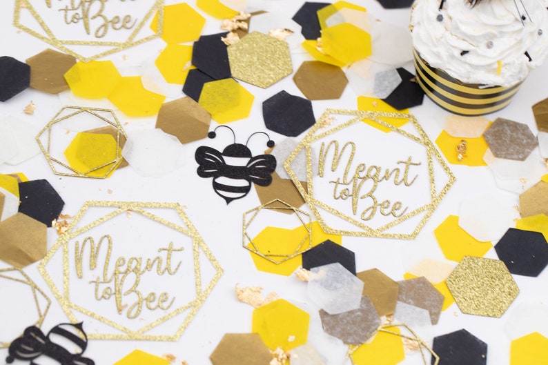 May include: Gold glitter confetti with black and yellow honeycomb shapes, a black and yellow bee cutout, and two gold glitter hexagon-shaped cutouts with the text "Meant to Bee".